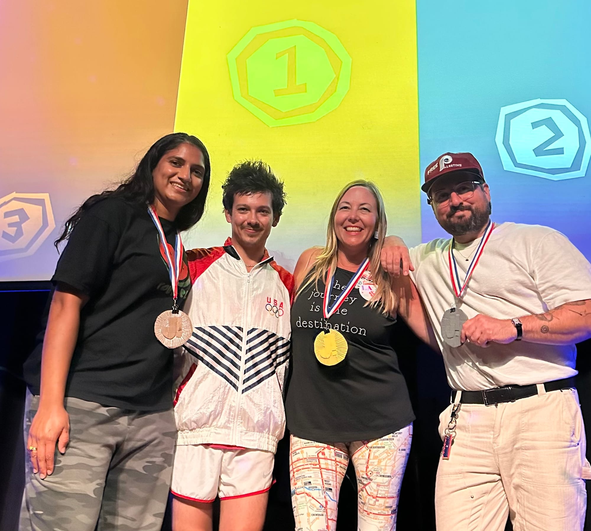 Four winners of the Jeopardy tournament standing before a screen with the gold, silver, and bronze labels behind