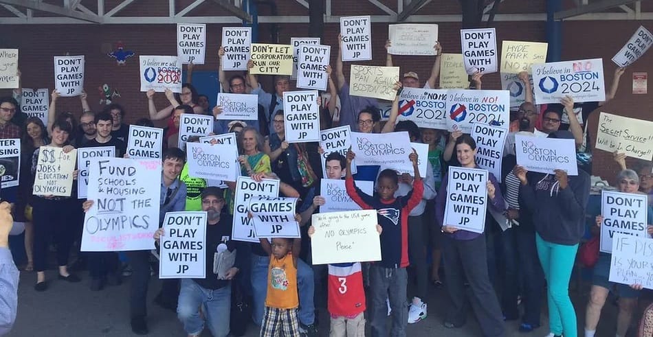 A large crowd of people holding signs that say "don't play games with JP" and "I believe in NO Boston Olympics"