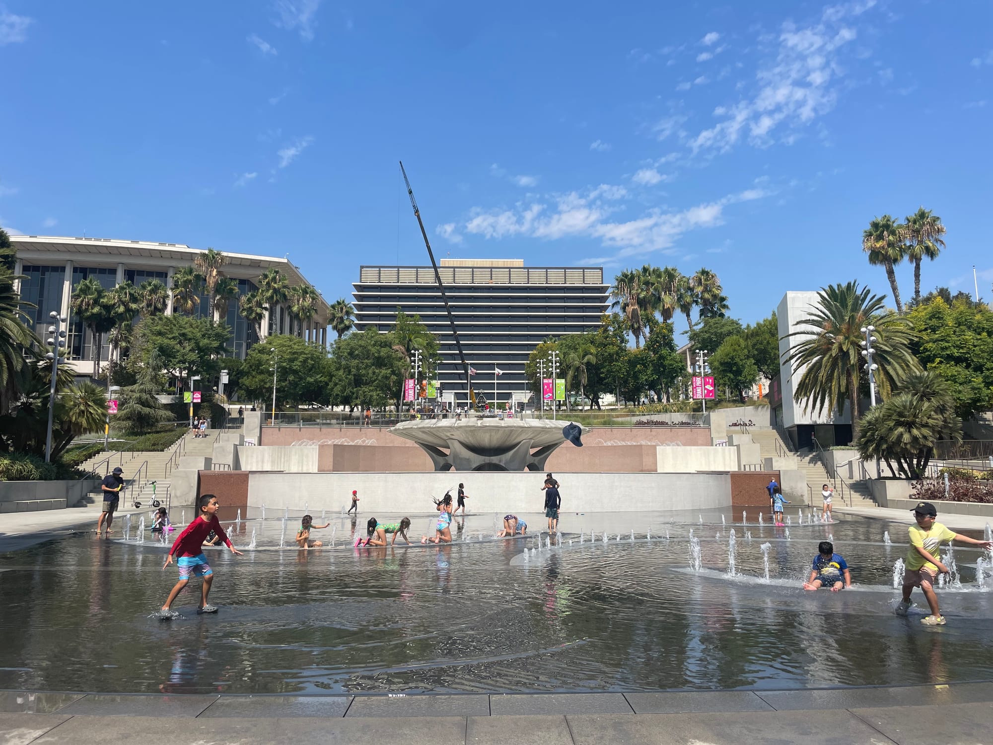 Kids play in the Grand Park splash pad, a broad city plaza with fountains and a wading pool