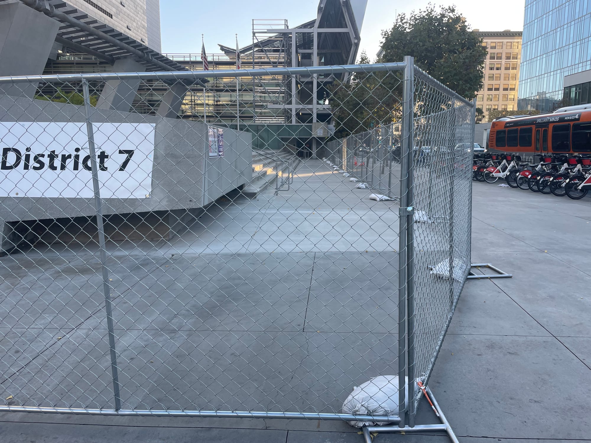 A large fence outside the Caltrans's plaza in downtown LA showing the stairs and walkway completely blocked off