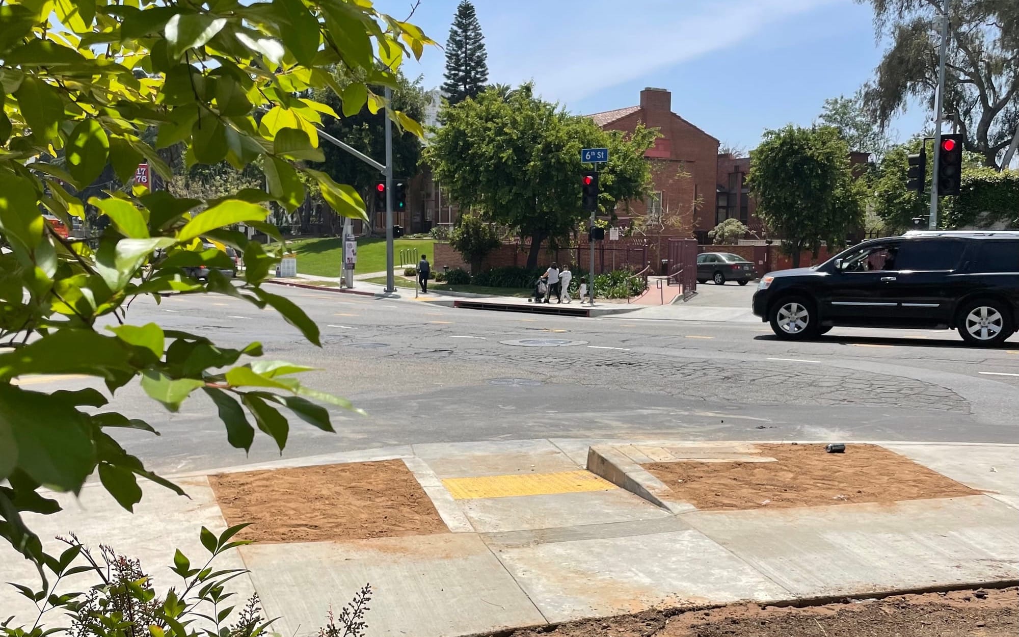 A clearly just-finished curb cut on a sidewalk that sends the person diagonally into the street instead of to a safe crossing