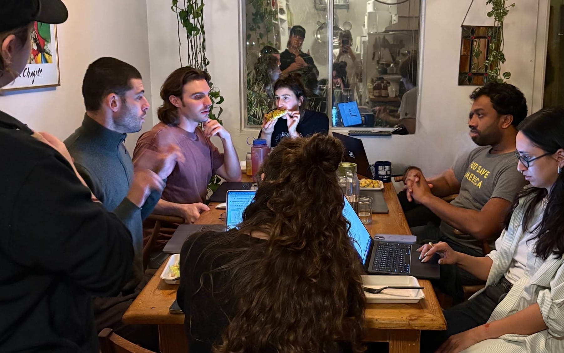 A group of people who are trying to find price gouging landlords sitting around a wooden table in an apartment with their laptops