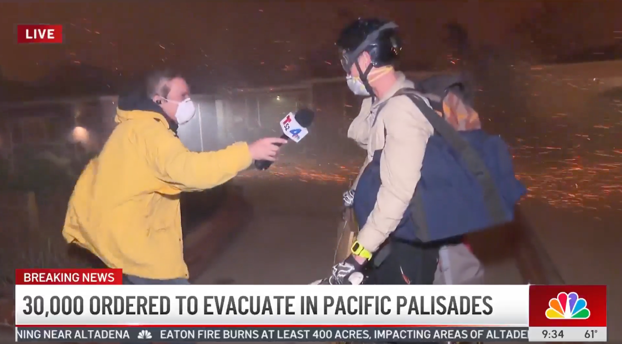 30,000 ordered to evacuate in Pacific Palisades reads the caption of the NBC LA news segment as a reporter in a mask in a raincoat interviews a person on a bike wearing goggles and a helment