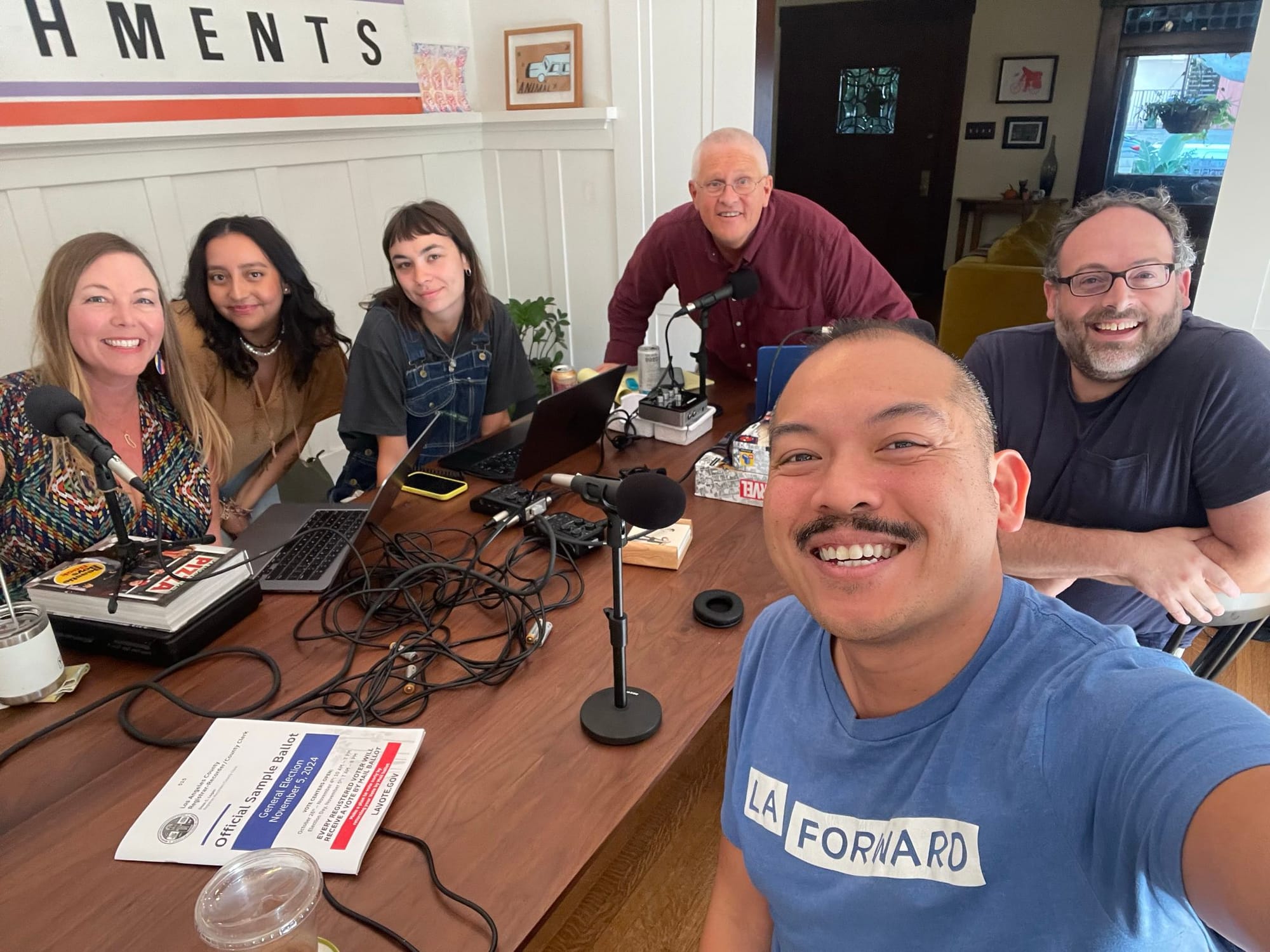 A group of LA Podcast hosts sitting around a table with recording gear